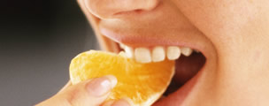 Mujer comiendo un gajo de naranja