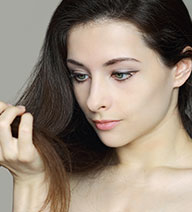 Mujer mirando su pelo negro con problemas capilares